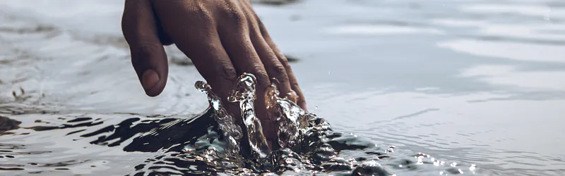 Hand dipping into water and splashing, evoking multisensory touch perception