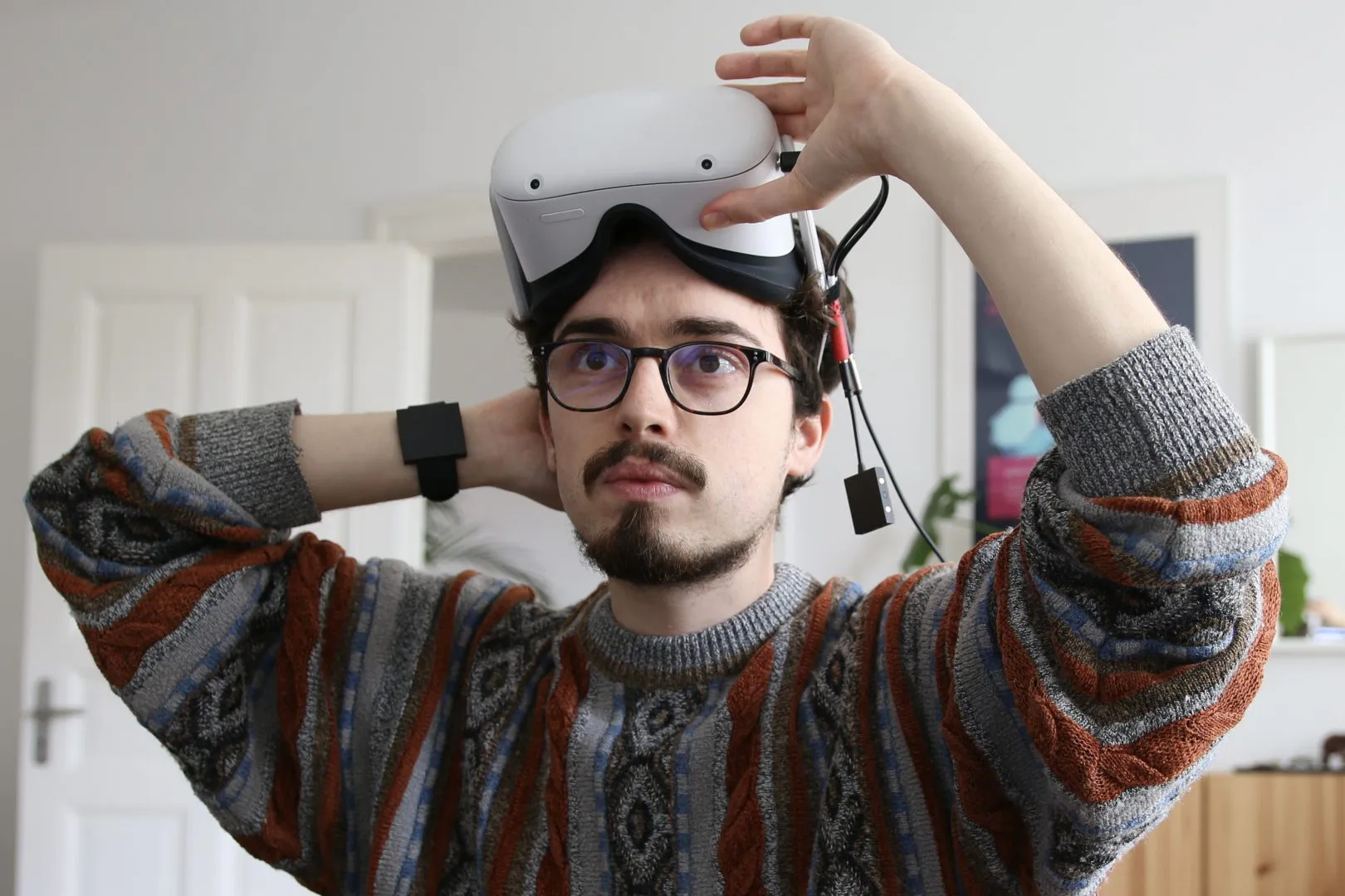 Simon Frübis lifting a VR headset while wearing his prototype haptic wristband