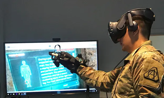 Soldier in a VR headset with haptic glove practicing a virtual medical training scenario