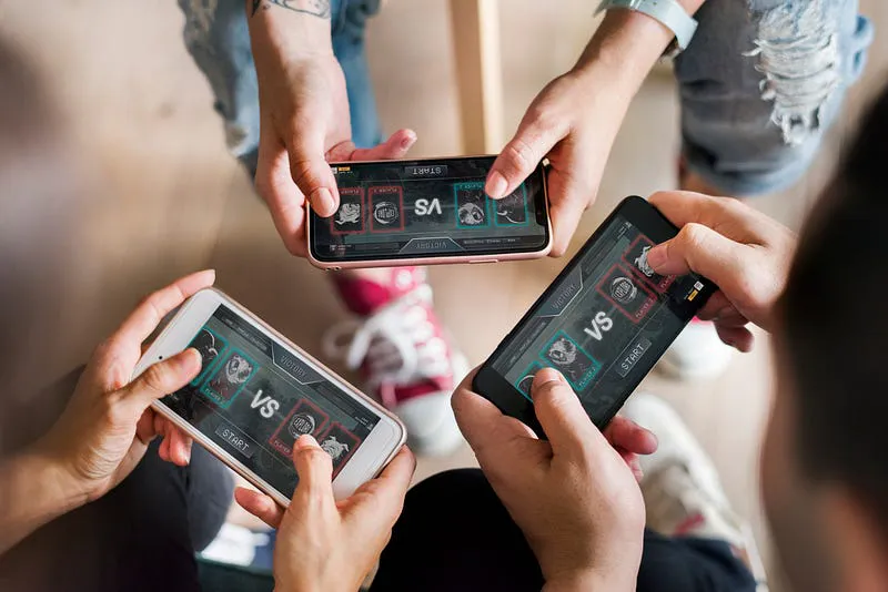 Three people playing a multiplayer versus game on their smartphones, showing the role of haptics in mobile gaming